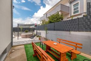 a patio with a wooden table and two benches at luxury apartment with garden jacuzzi in Trogir