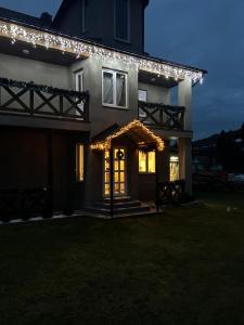 ein Haus mit Lichtern an der Vorderseite in der Nacht in der Unterkunft Карпатські Зорі in Pilipets