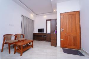 a living room with a wooden door and a table and chairs at Le Eden Resort in Sultan Bathery