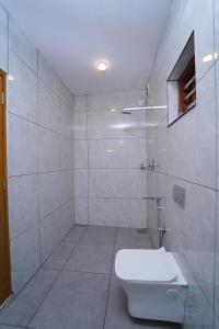 a white bathroom with a toilet and a shower at Le Eden Resort in Sultan Bathery