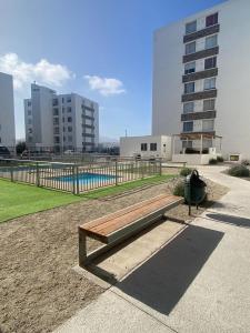 Hermoso departamento a pasos de avenida del mar في لا سيرينا: مقعد في حديقة مع مسبح ومباني