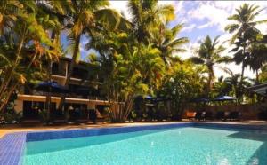 una piscina frente a un complejo con palmeras en Oasis Palms Hotel, en Nadi