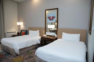 um quarto de hotel com duas camas e um espelho em Pearl Continental Hotel, Bhurban em Bhurban