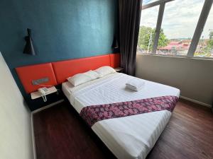 una camera da letto con letto con testiera arancione e finestra di Win Win Boutique Hotel PD a Port Dickson