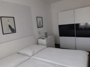 ein weißes Schlafzimmer mit einem Bett und einem TV in der Unterkunft Ferienwohnung Leithaberg in Eisenstadt