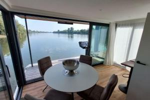 uma mesa e cadeiras num quarto com vista para um lago em Riverboat-Rhein-Main Ferienloft em Wiesbaden