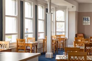 een restaurant met tafels, stoelen en ramen bij The County Hotel in Llandudno