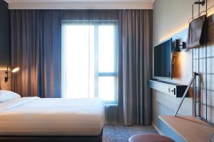 une chambre d'hôtel avec un lit et une télévision dans l'établissement Moxy Brussels City Center, à Bruxelles