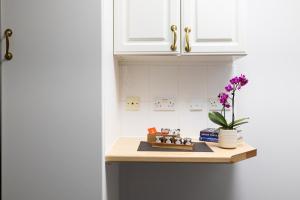 a kitchen counter with a vase with purple flowers on it at Charmstay Swiss Cottage in London