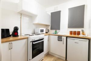 a kitchen with white cabinets and white appliances at Charmstay Swiss Cottage in London