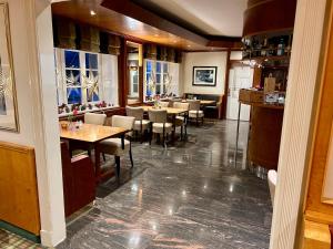 a dining room with tables and chairs and windows at Hotel Maack in Seevetal