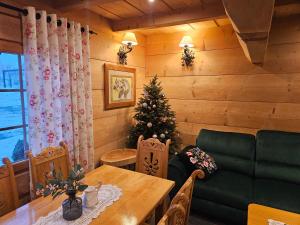 een woonkamer met een kerstboom en een tafel bij Domek Góralski Amelka in Poronin