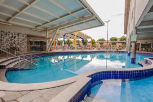 - une grande piscine avec des carreaux bleus dans un bâtiment dans l'établissement DiRoma Fiori Hotel - BVTUR, à Caldas Novas