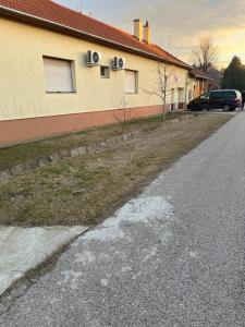 une maison avec une voiture garée à côté d'une rue dans l'établissement Abigél Apartman, à Mórahalom