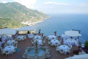 a restaurant with white tables and chairs and the ocean at Hotel Villa Fraulo in Ravello