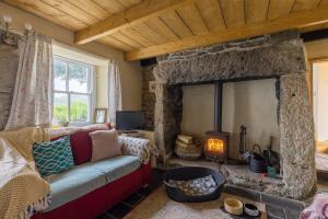 sala de estar con chimenea de piedra y sofá en Kitts Cottage Redruth, en Redruth