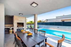 comedor con mesa y piscina en Villa Lorena Dalmacija, en Nin