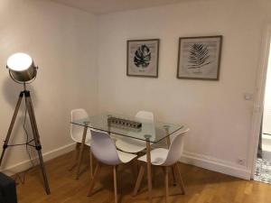 un tavolo in vetro con sedie bianche in una stanza di Appartement 2/3 pièces (55m²) au cœur du Vexin a Chars