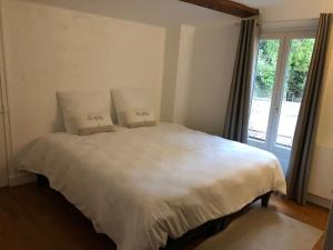 una camera da letto con un grande letto bianco con due cuscini di Appartement 2/3 pièces (55m²) au cœur du Vexin a Chars