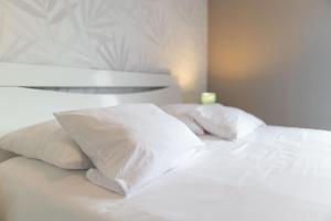 a bed with white sheets and pillows on it at Appartement Les Oiseaux in Thionville