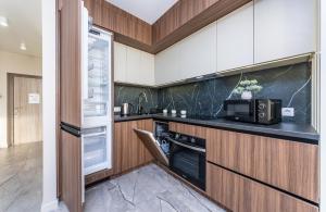 y cocina con nevera y microondas. en FlatRent Olympic Park, генератор в будинку, метро поруч!, en Kiev