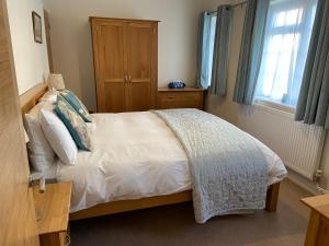 - une chambre avec un lit blanc et une armoire en bois dans l'établissement The Bothy, à Lyndhurst