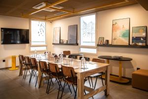 Habitación con una mesa larga con sillas y ventanas. en JOST Hôtel Le Havre Centre Gare, en Le Havre