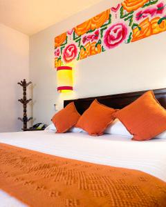 1 dormitorio con 1 cama con almohadas de color naranja en Parador del Dominico, en Oaxaca City