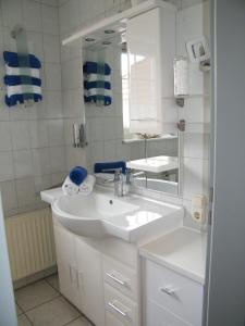 Baño blanco con lavabo y espejo en Ferienwohnung Seeblick - b47745, en Neuharlingersiel