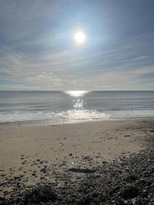 una playa con el sol saliendo sobre el océano en The Studio in Climping, en Climping