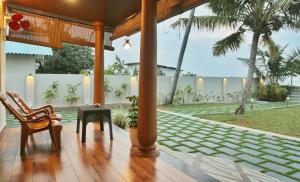 une véranda avec des chaises, une table et des palmiers dans l'établissement SHORE STORIES, à Alappuzha