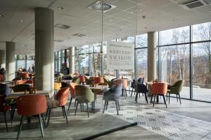 um restaurante com mesas, cadeiras e janelas em Złoty Horyzont Hotel & Resort Szklarska Poręba em Szklarska Poręba