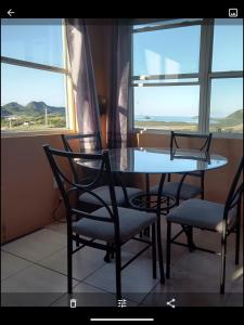 een eettafel met 2 stoelen en een tafel en 2 ramen bij Zeus Estate Guesthouse in Grays Hill