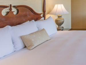 uma cama com almofadas brancas e um candeeiro em The Brown Hotel em Louisville