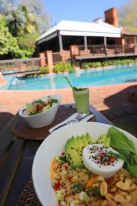 ein Teller mit Essen auf einem Tisch neben einem Pool in der Unterkunft Hotel L'Auberge in Punta del Este