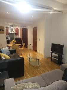 a living room with a couch and a table and a piano at Fantastic 2 bedroom apartment in Manchester