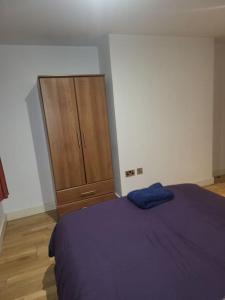 a bedroom with a bed and a wooden cabinet at Fantastic 2 bedroom apartment in Manchester