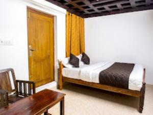 a bedroom with a bed and a table and a wooden door at Keloth Tharavad Kerala in Panamaram