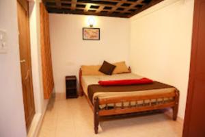 a bedroom with a bed with a red pillow on it at Keloth Tharavad Kerala in Panamaram