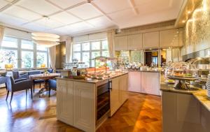 une grande cuisine avec des placards blancs et une salle à manger dans l'établissement Hotel Villa Elben Lörrach bei Basel, à Lörrach