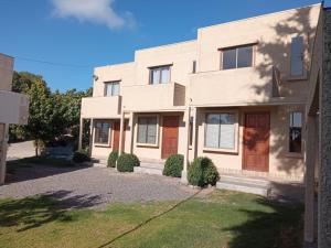 Casa blanca con puertas marrones y entrada en Cabanas Piedras Preciosas, en El Quisco