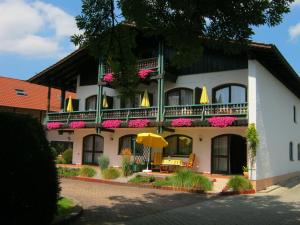 ein großes weißes Gebäude mit einem Balkon mit rosa Blumen in der Unterkunft Landhaus Cornelia in Bad Birnbach