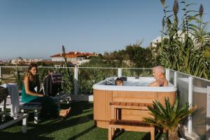 een man in een bubbelbad op een balkon met twee vrouwen bij We Surf House in Figueira da Foz