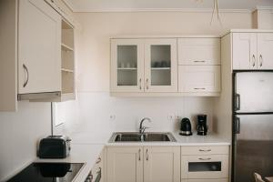 a kitchen with white cabinets and a sink and a refrigerator at Nereides Luxury Villas in Káto Almirí