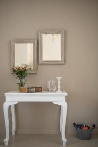 a white console table with a mirror and flowers on it at Nereides Luxury Villas in Káto Almirí