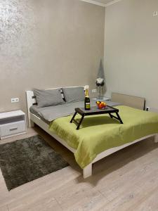 Truskavets Oasis Apartments في تريسكوفيتس: سرير مع طاولة عليها زجاجة وفواكه