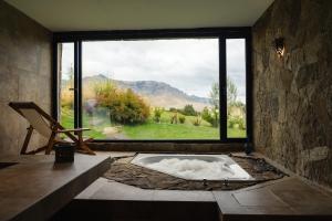 a bath tub in a room with a large window at Loi Suites Chapelco Hotel in San Martín de los Andes