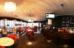 a restaurant with a bar with red chairs and a television at Hotel Premier in Cluj-Napoca