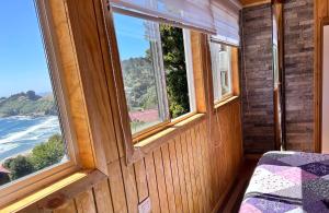 a room with two windows and a bed and the ocean at Cabañas Emma Maicolpue in Osorno