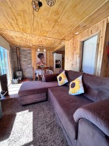 a living room with a brown couch and a table at Cabañas Emma Maicolpue in Osorno